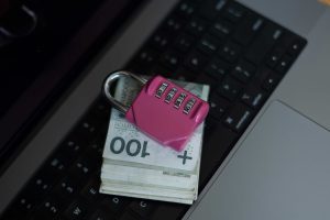 Imagen de un teclado de portátil con dinero encima y un candado.