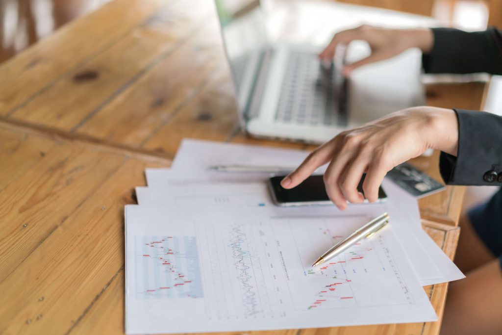 Imagen de mesa con papeles de trading y una pantalla de portatil