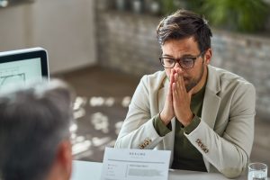 Despacho con un hombre con gesto preocupado frente otro hombre que está revisando una documentación